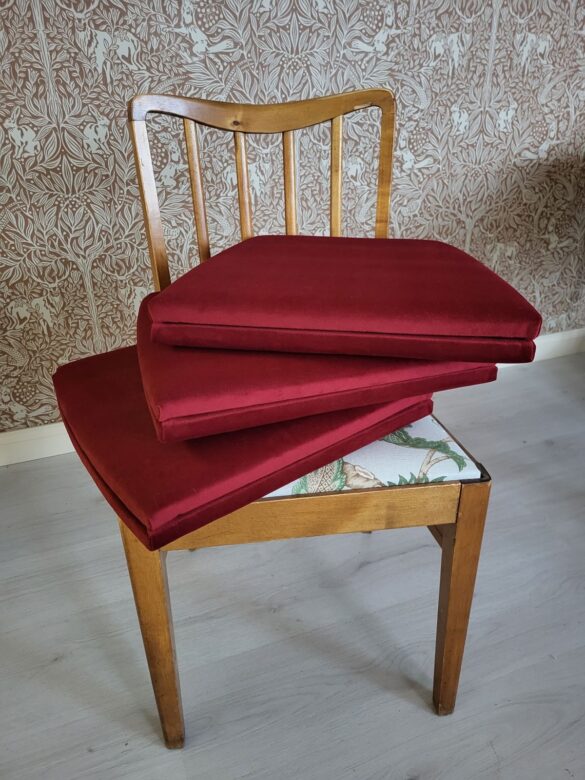 Pikkutuolien istuimien uusi verhoilu punaisella samettikankaalla.