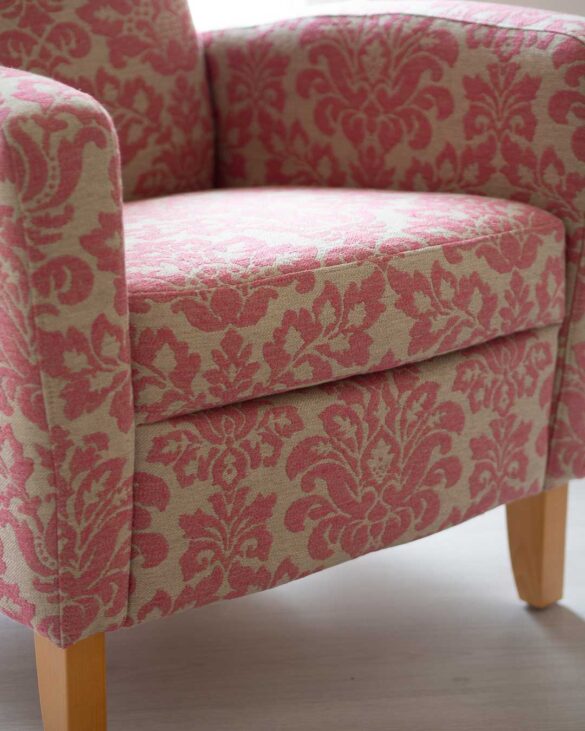 Uudelleenverhoiltu nojatuoli kuviollisella pinkillä kankaalla.