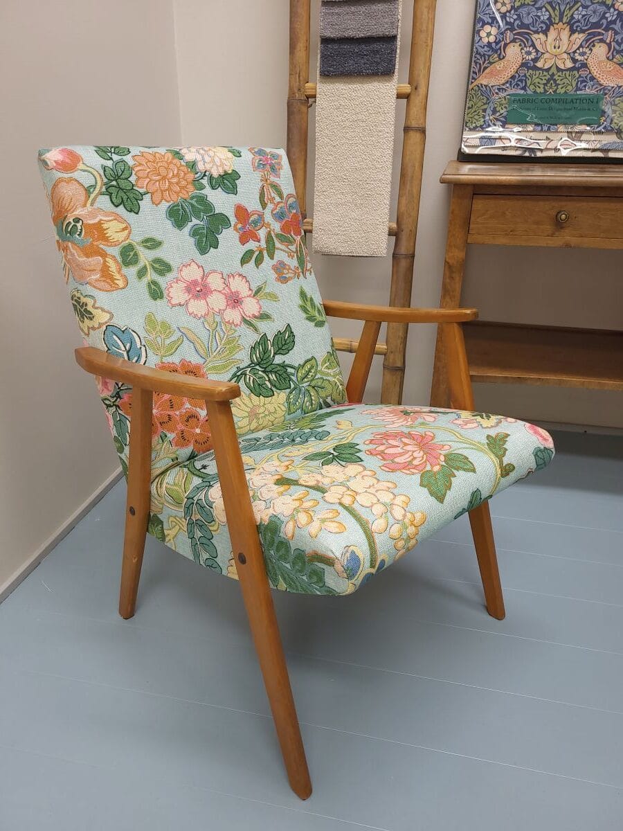 Vanha 1950-luvun lepotuoli verhoiltuna Lauritzonin kukkakuvioisella huonekalukankaalla.
