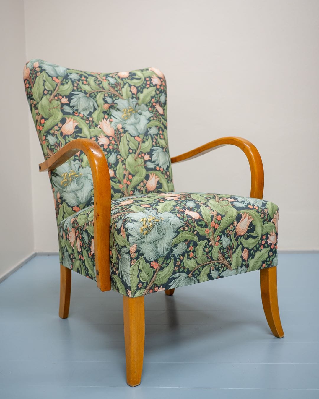 Vanha K-tuoli verhoiltuna sinivihreällä kukkakuvioisella huonekalukankaalla.