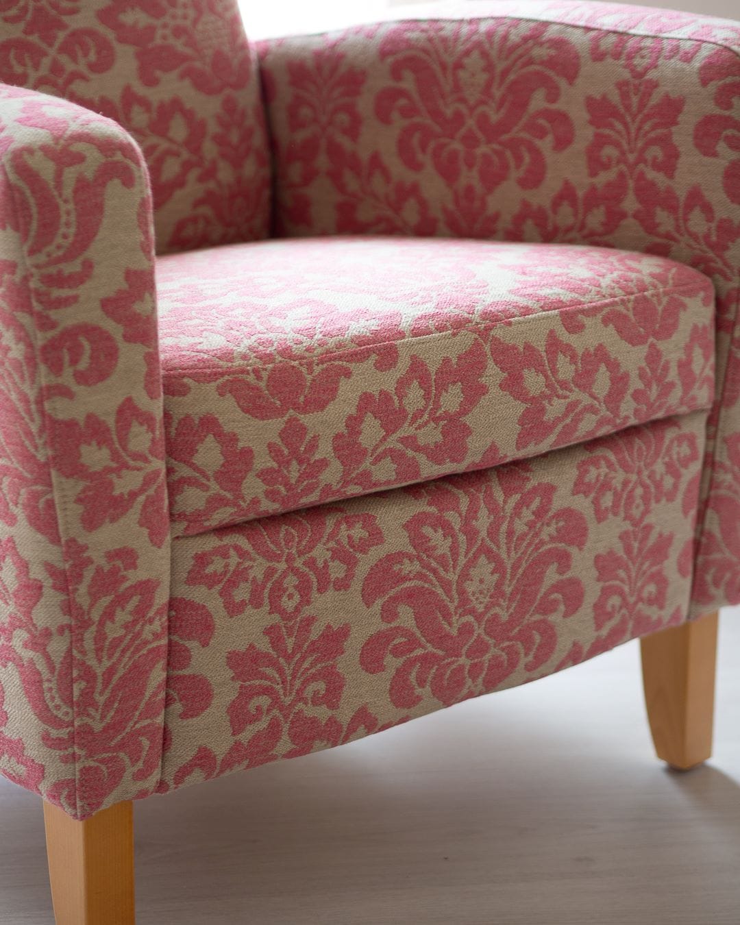 Iskun vanha nojatuoli verhoiltuna uudella pinkkikuvioisella huonekalukankaalla.